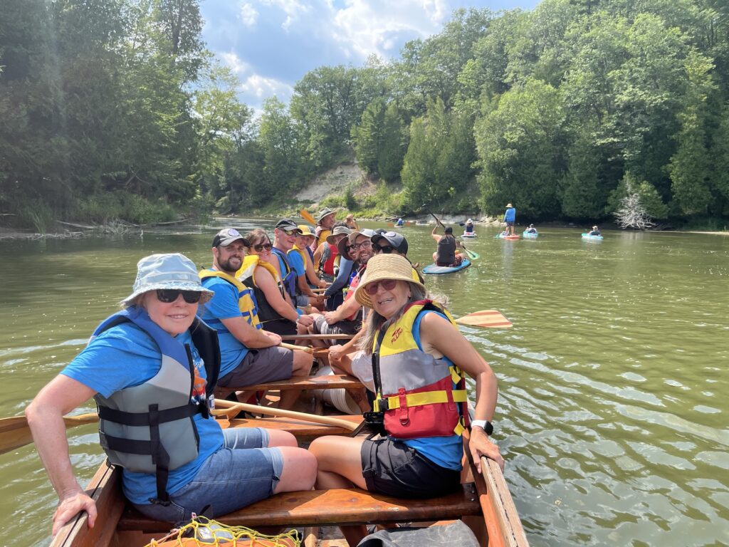 Group of smiling paddlers in a voyageur canoe
